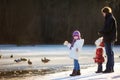 Father and his daughters feeding ducks at winter Royalty Free Stock Photo