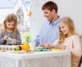 Father and his daughters painting and decorating easter eggs. Royalty Free Stock Photo