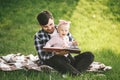 Father and his little baby daugter reading book in a park