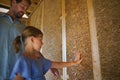 Father with his little daughter checking their unfinished wooden house, diy eco-friendly homes concept. Royalty Free Stock Photo