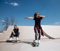 Father and his little son dressed in the casual clothes ride skateboards and have fun in a skate park with slides Royalty Free Stock Photo