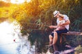Father with his little son are fishing while sitting on a wooden pier by the pond Royalty Free Stock Photo
