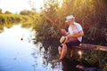 Father with his little son are fishing while sitting on a wooden pier by the pond Royalty Free Stock Photo