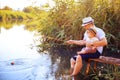 Father with his little son are fishing while sitting on a wooden pier by the pond Royalty Free Stock Photo