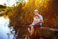 Father with his little son are fishing while sitting on a wooden pier by the pond Royalty Free Stock Photo