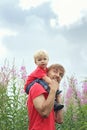 Father and his little son have fun on blooming fireweed field. C