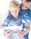 Father and his little son playing together on mobile computer, resting indoor.Bearded man with young boy using tablet PC Royalty Free Stock Photo