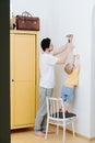 Father with a small toddler son are attaching framed drawing to the wall