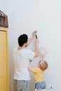 Father with a small toddler son are attaching framed drawing to the wall