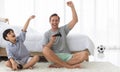 Father and his mixed-race son holding controller joystick to play a game together with fun and happy in bedroom Royalty Free Stock Photo