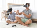 Father and his mixed-race son wearing vr virtual reality device to play a game together with fun and happy in bedroo Royalty Free Stock Photo