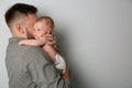 Father with his newborn son on grey background. Space for text Royalty Free Stock Photo