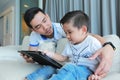 Father and his son happy having fun by gaming on a tablet.