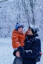 Father and his son playing outside, winter forest on the background, snowing, happy and joyful Royalty Free Stock Photo