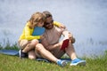 Father with his son reading book together in the summer park. Father and son having a picnic in the park, happiness Royalty Free Stock Photo