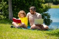 Father with his son reading book together in the summer park. Father and son having a picnic in the park, happiness Royalty Free Stock Photo