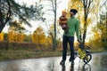 Father and his tiddler son walking in the park on good autumn day. Dad holding kid in one hand and child`s bicycle in another Royalty Free Stock Photo