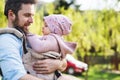 A father with his toddler daughter in a baby carrier outside on a spring walk. Royalty Free Stock Photo