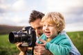 A father and his toddler son with a camera outside in spring nature. Royalty Free Stock Photo