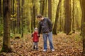 Father and his toddler son walking during the hiking activities in autumn forest at sunset Royalty Free Stock Photo