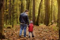 Father and his toddler son walking during the hiking activities in autumn forest at sunset Royalty Free Stock Photo