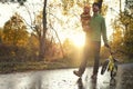 Father and his toddler son walking in the park on good autumn day. Dad holding kid in one hand and child`s bicycle in another.