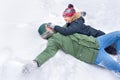 A father with his 10-year old son is playing with the snow lying in the snow