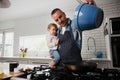 Father holding daughter on his hip while pouring baking batter into pan.