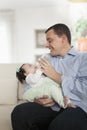 Father holding and feeding his baby daughter on the couch Royalty Free Stock Photo