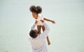 Father holding his daughter up high against sky. african american dady hug girl with sea background Royalty Free Stock Photo