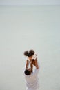 Father holding his daughter up high against sky. african american dady hug girl with sea background Royalty Free Stock Photo