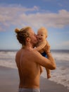 Father holding, kissing his infant baby boy son high in the air on sandy beach. Family travel and summer vacations concept. Family Royalty Free Stock Photo