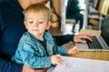 Father holding little baby son and working on laptop at home. Concept of remotely work Royalty Free Stock Photo