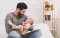 Father holding and soothing crying newborn baby in his arms