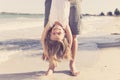 Father holding sweet young and lovely blond small daughter by her feet playing having fun on the beach in dad and little girl love Royalty Free Stock Photo