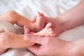 Father holds the feet of a newborn baby in his arms. Hands and feet on a white background close-up. Royalty Free Stock Photo