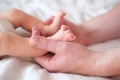 Father holds the feet of a newborn baby in his arms. Hands and feet on a white background close-up Royalty Free Stock Photo