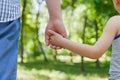 Father holds the hand of a little child in sunny park outdoor, united family concept