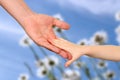 A father holds the hand of a small child on a blue background