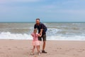 Father holds his cute daughter in arms, circles around himself, play have fun together on sea beach. Father s Day family Royalty Free Stock Photo