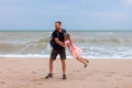 Father holds his cute daughter in arms, circles around himself, play have fun together on sea beach. Father`s Day family Royalty Free Stock Photo