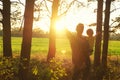 Father holds his toddler son in his arms and they open hands togerher to meet beautiful sunset on the edge of forest. Father`s da