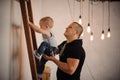 Father at home helping his little son climbing slowly up the lad Royalty Free Stock Photo