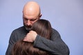 Father hugging his daughter . Man in his 40s, bald with grey beard. girl teenager with long hair. Blue background