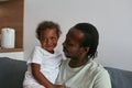 Father hugging joyful daughter on sofa at home