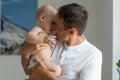 Father Hugging Newborn Baby in white bedroom. Royalty Free Stock Photo