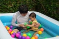 father and infant baby girl playing water with colorful plastic balls in inflatable pool Royalty Free Stock Photo