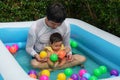 father and infant baby girl playing water with colorful plastic balls in inflatable pool Royalty Free Stock Photo