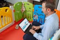 Father inside baby playpen using laptop with business graphics on the screen