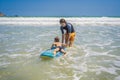 Father or instructor teaching his son how to surf in the sea on vacation or holiday. Travel and sports with children